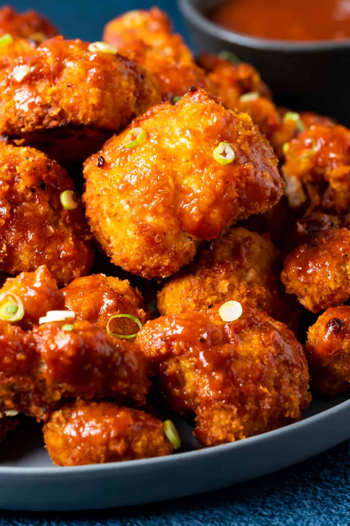 BBQ cauliflower wings on a plate with chopped spring onions.