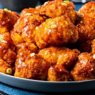 BBQ cauliflower wings on a plate with chopped spring onions.