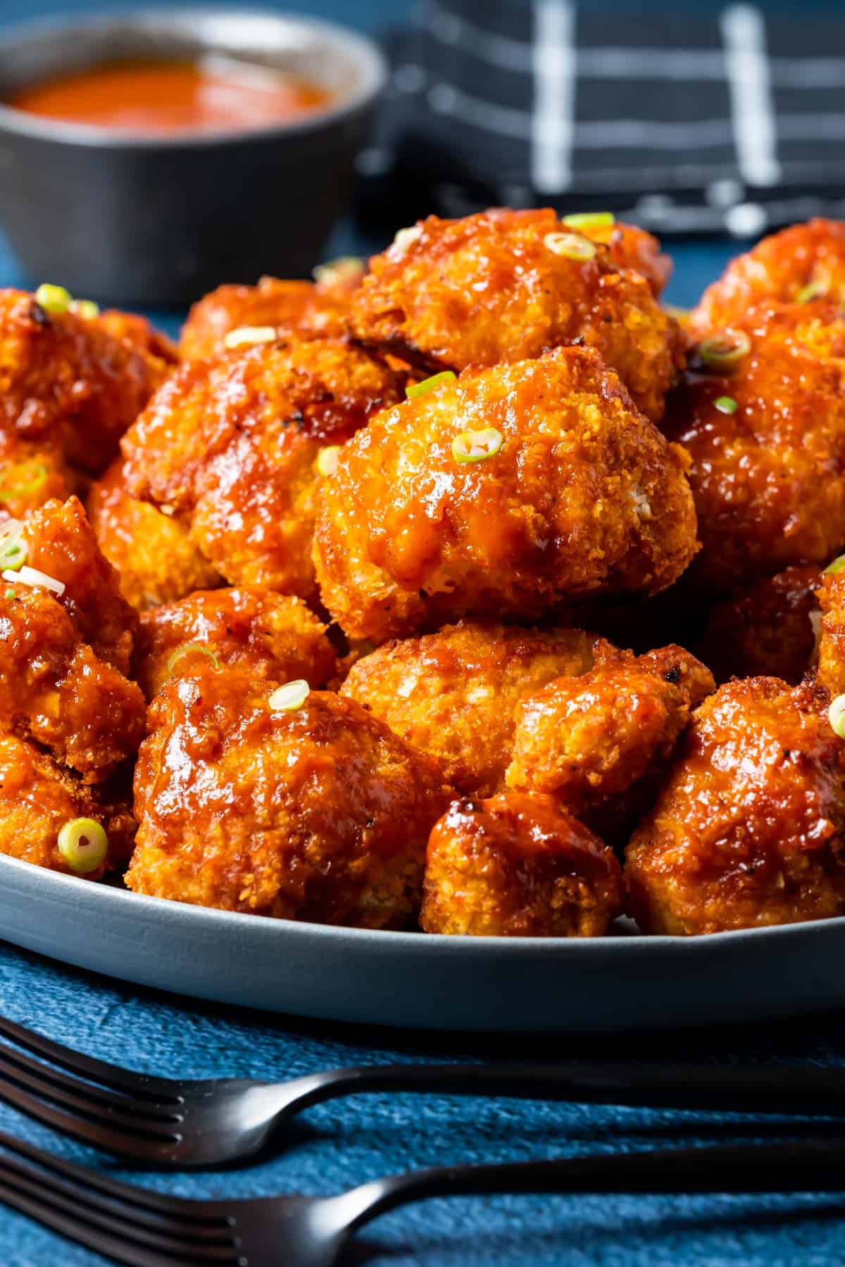 BBQ cauliflower wings on a plate with chopped spring onions.