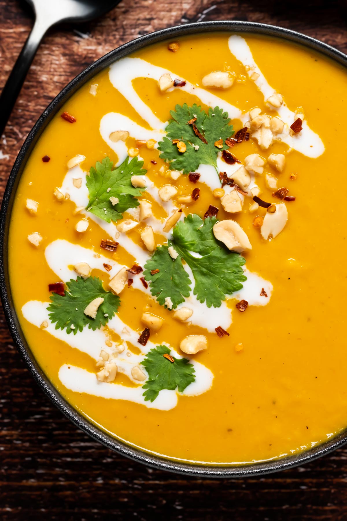 Thai butternut squash soup in a bowl topped with crushed peanuts and fresh cilantro.