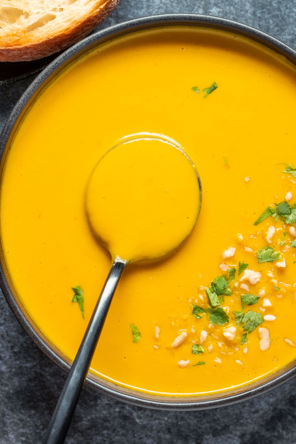 Vegan carrot soup in a black bowl with a spoon.