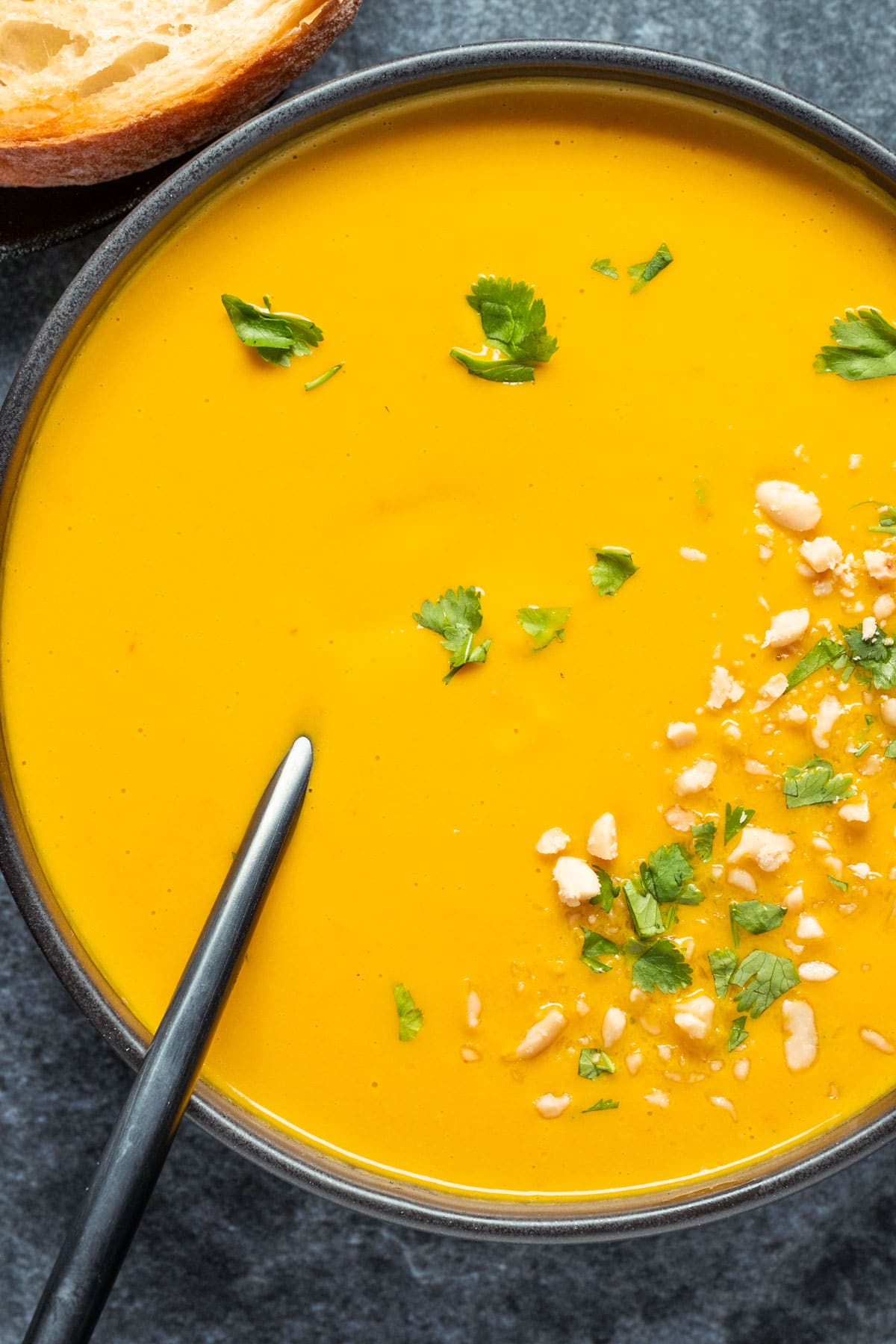 Vegan carrot soup in a black bowl with a spoon.