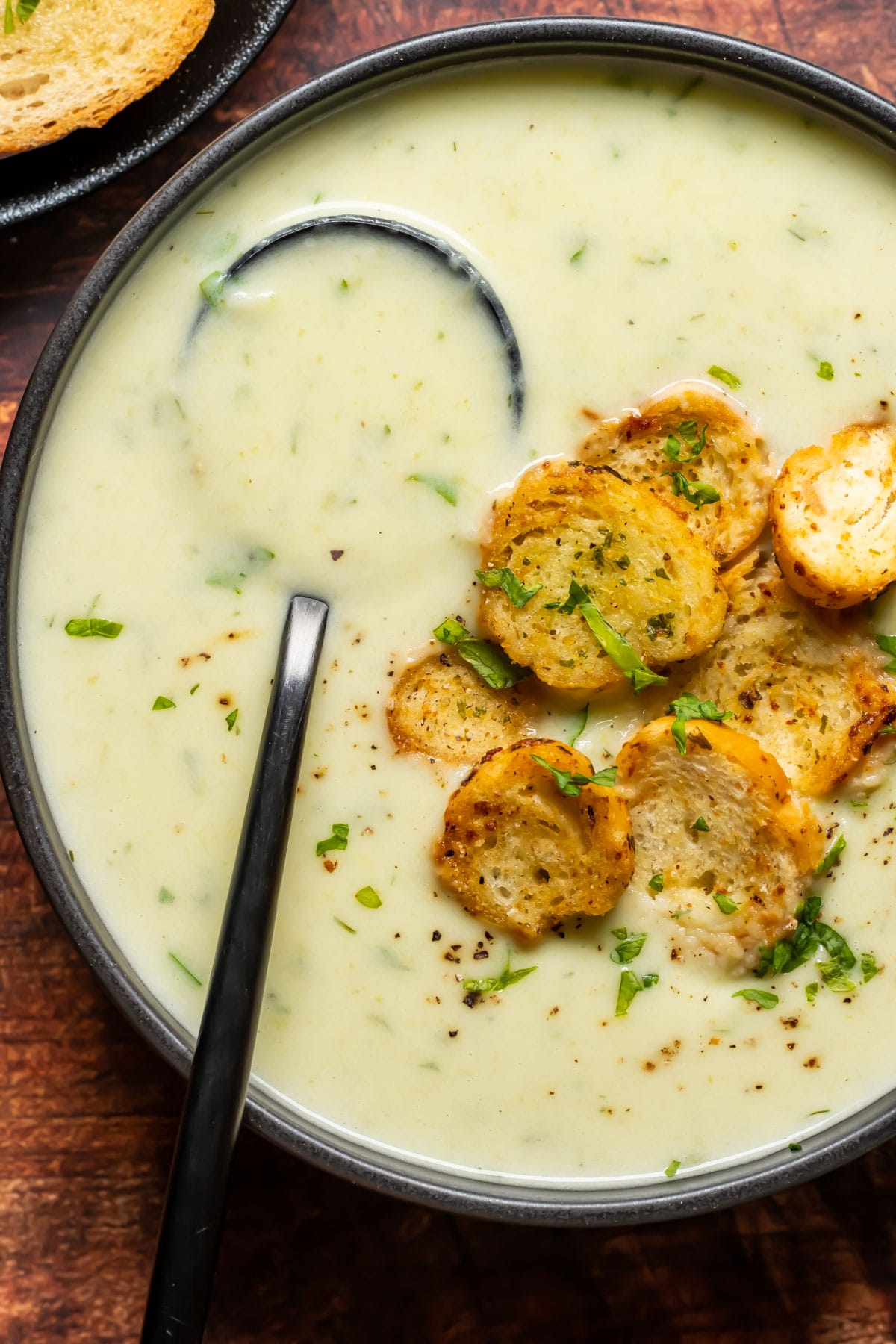 Vegan celery soup in a black bowl with a spoon.