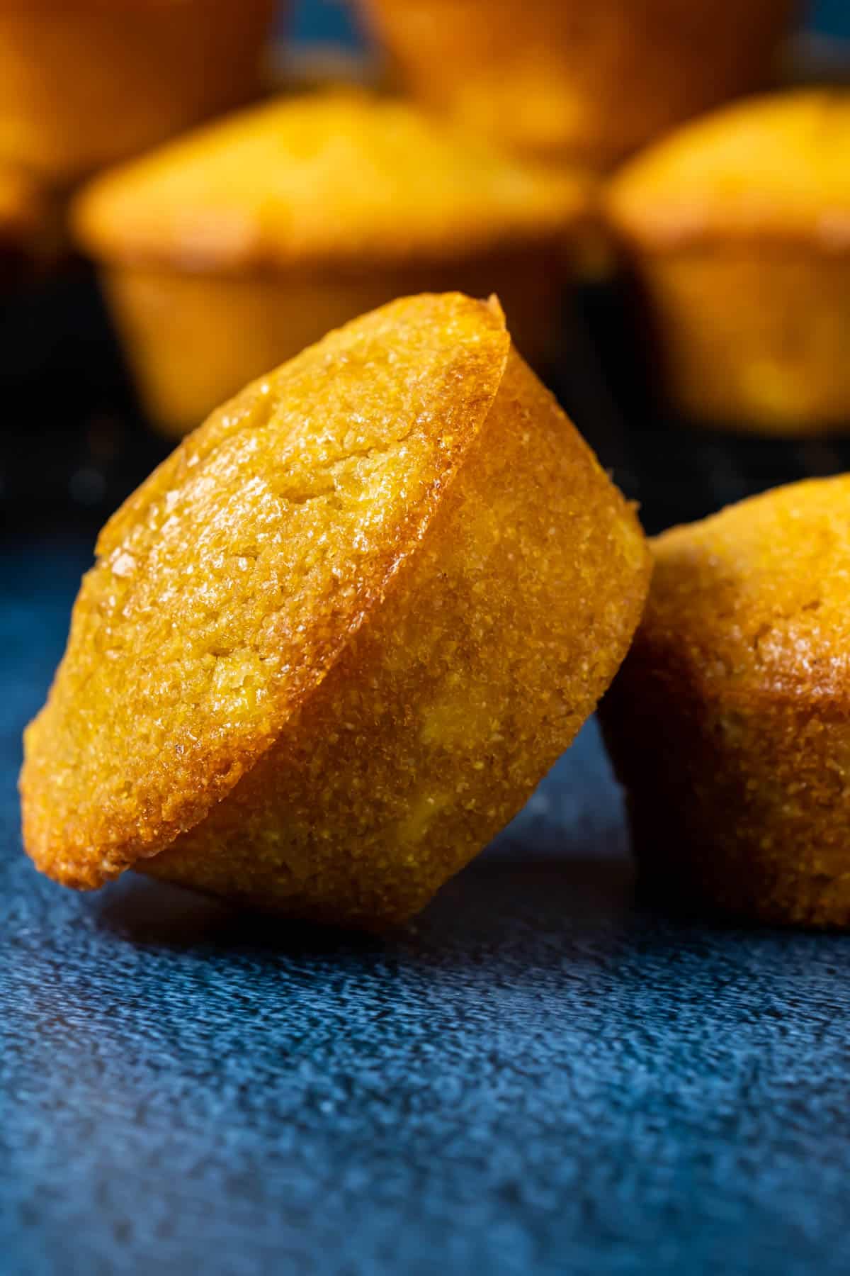 Vegan cornbread muffin leaning against another muffin.