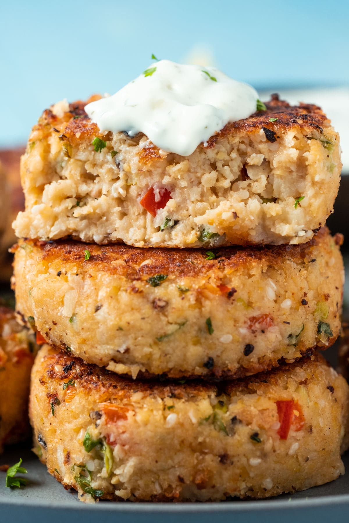 Stack of vegan crab cakes topped with vegan tartar sauce.