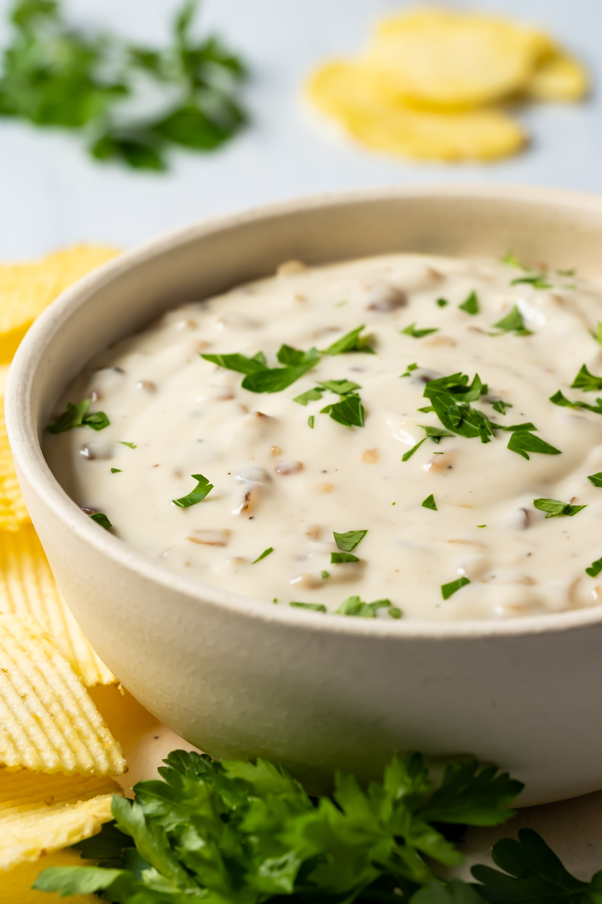 Vegan French onion dip topped with fresh parsley in a white bowl.