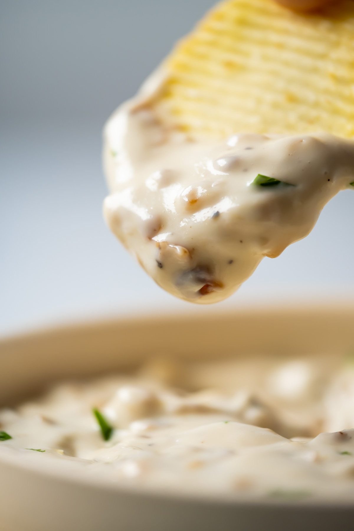 Chip dipping into a bowl of French onion dip.