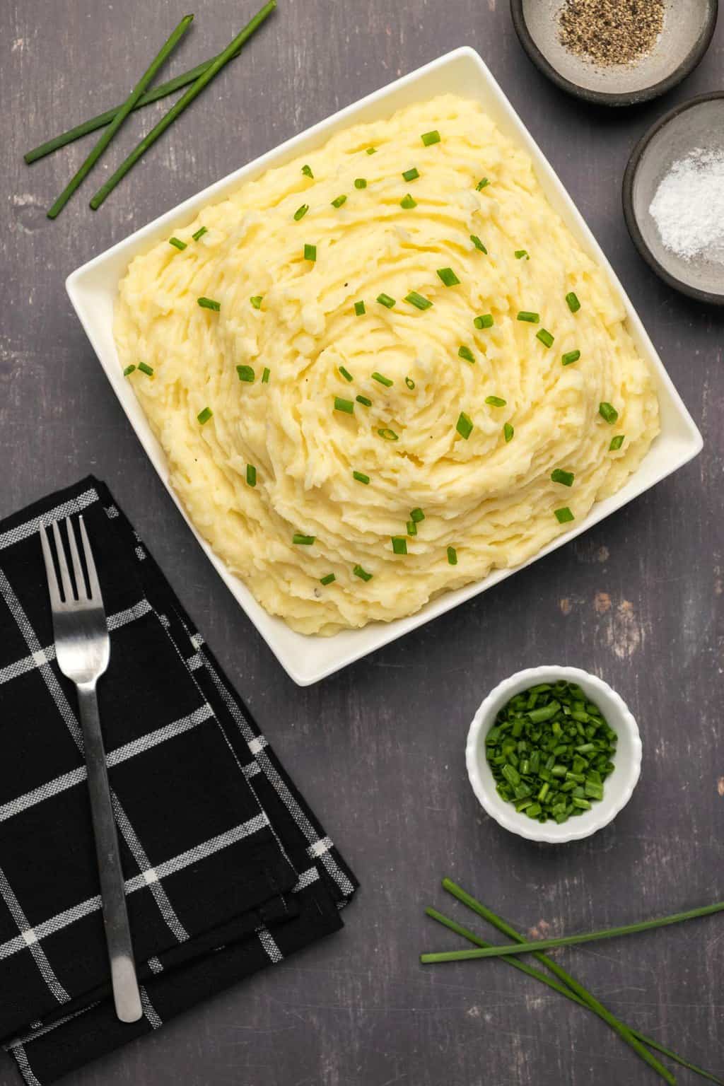 Vegan mashed potatoes topped with chopped chives in a white dish. 