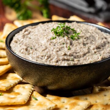 Vegan mushroom pâté in a black bowl with crackers.