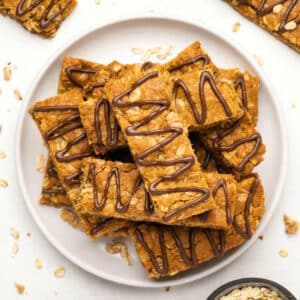 Vegan oatmeal bars stacked up on a white plate.