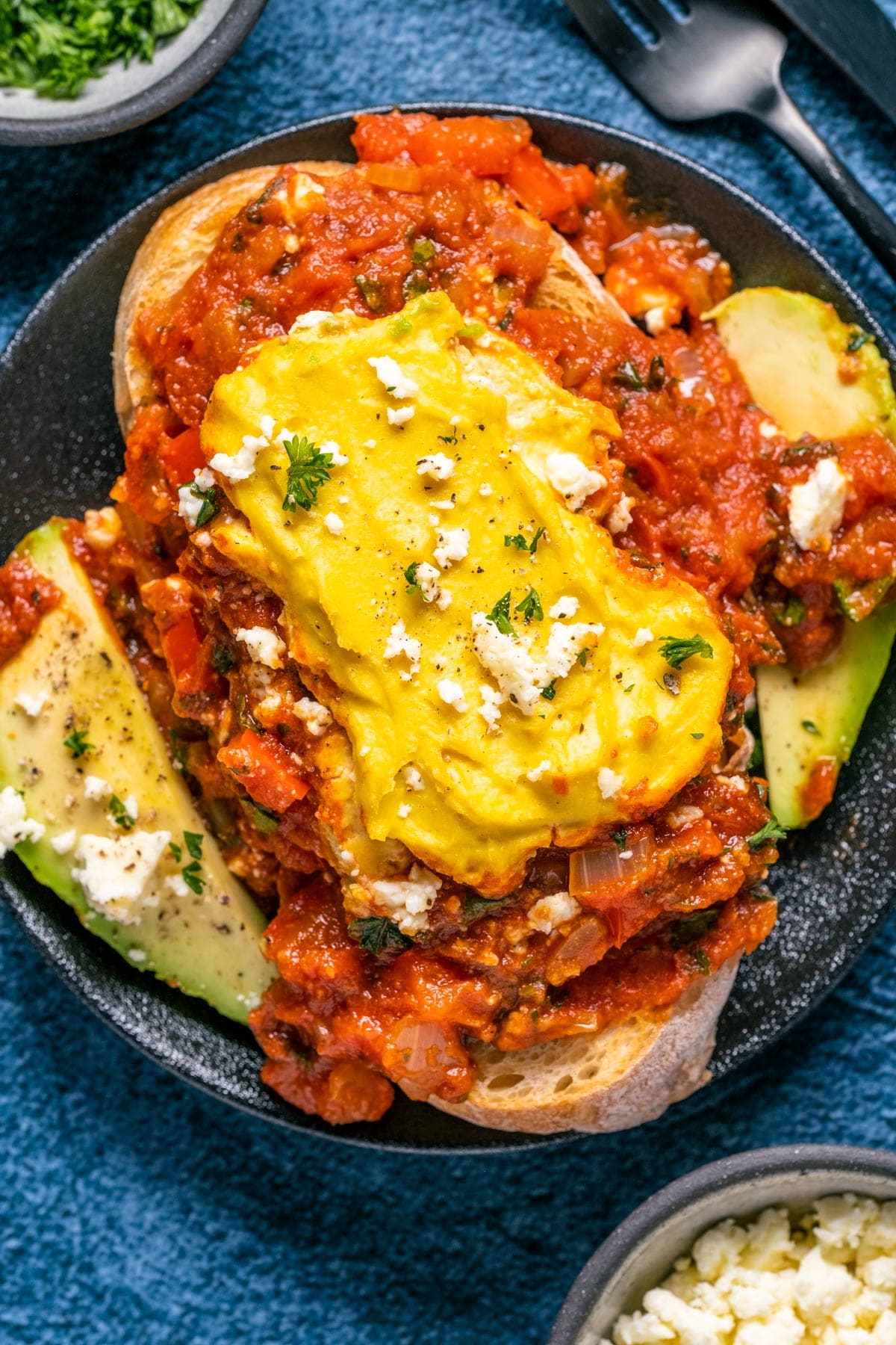 Serving of vegan shakshuka with toast on a black plate.