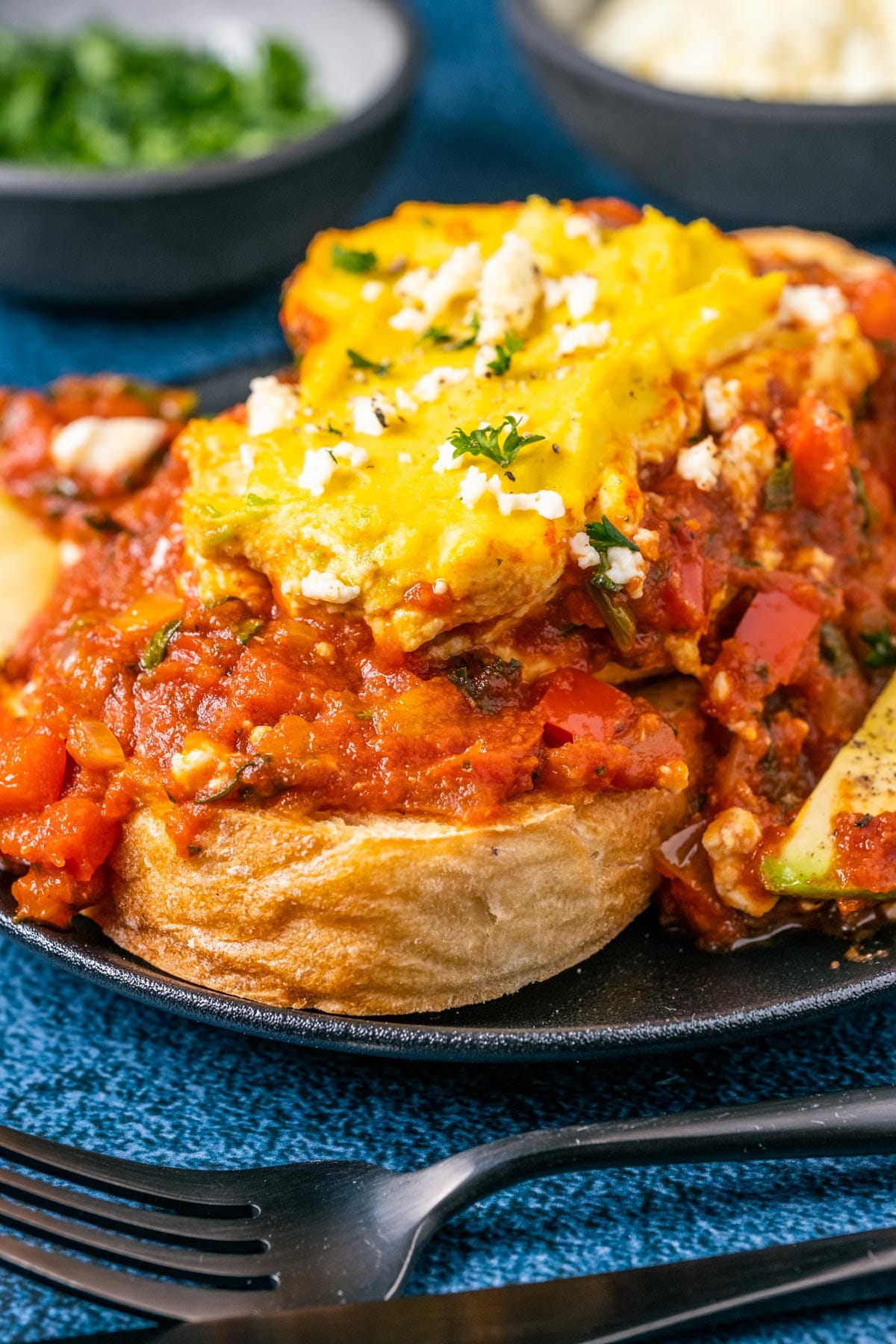 Serving of vegan shakshuka with toast on a black plate.