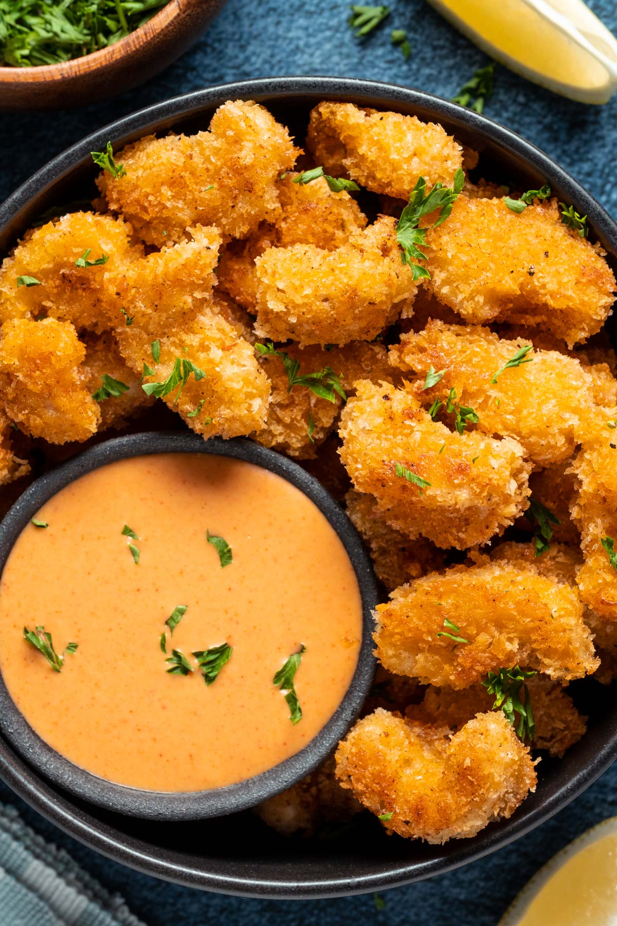 Vegan shrimp stacked up on a plate with a bowl of yum yum sauce on the side.